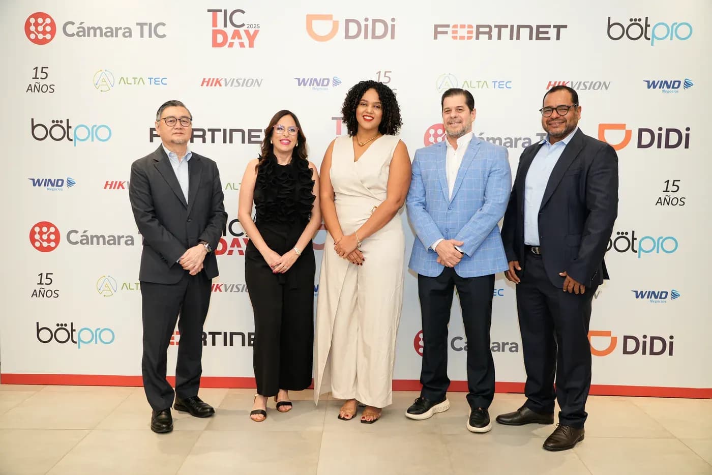TIC DAY 2025: cinco asistentes posan frente al panel de aliados del evento